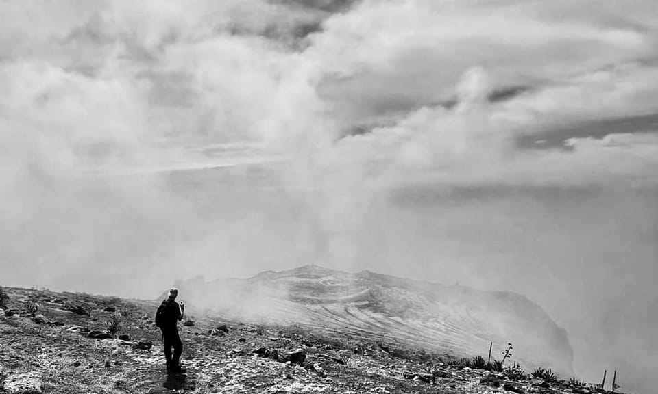 Schwarzweiß-Aufnahme einer neblig-wolkige Vulkanlandschaft auf Teneriffa mit einem einzelnen Wanderer im Vordergrund.